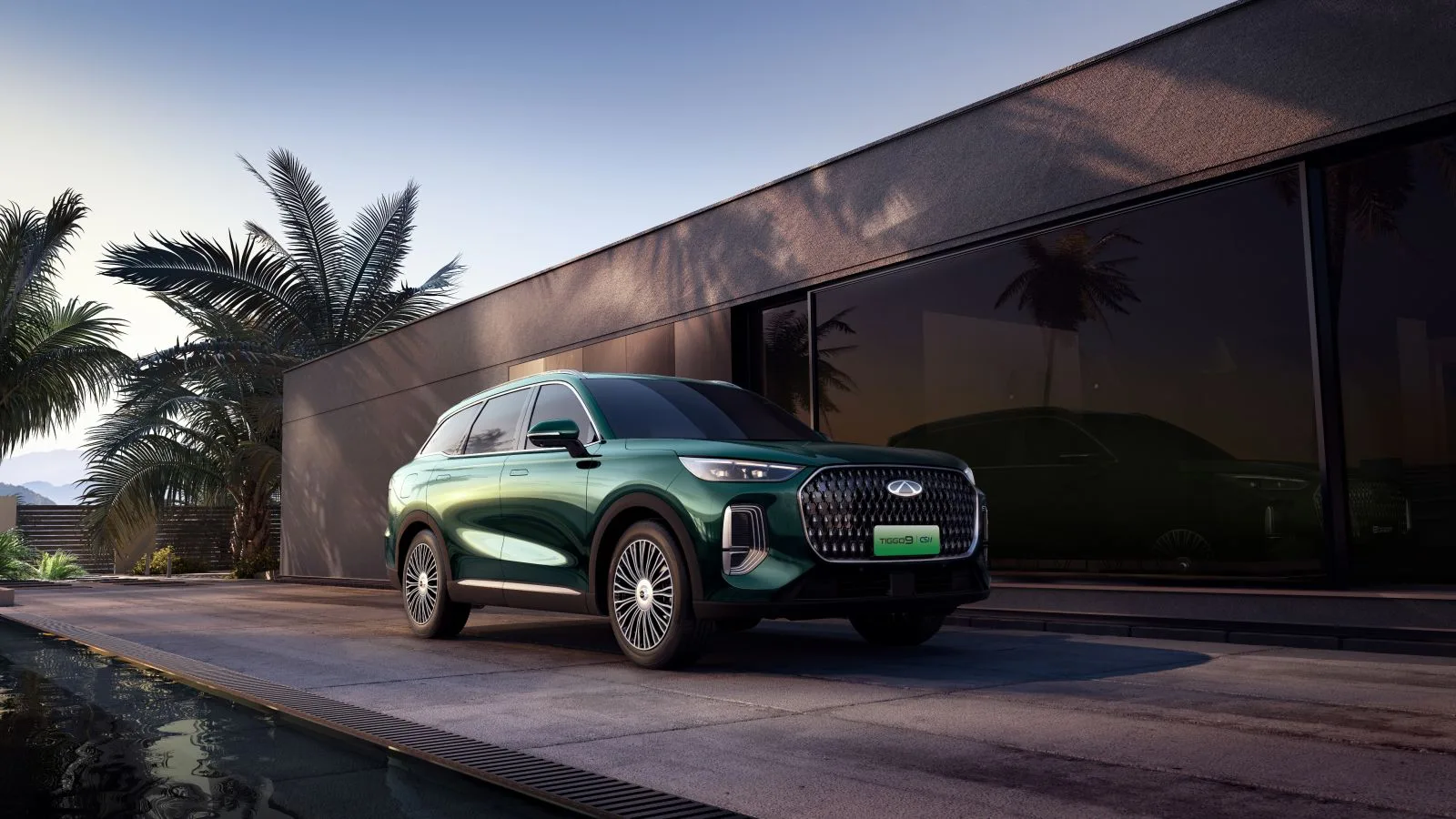 Chery TIGGO 9 PHEV in Waldgrün vor einem modernen Gebäude in der Abenddämmerung
